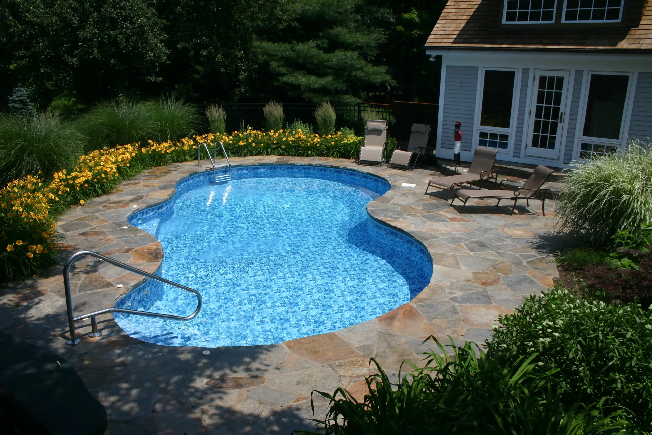 Custom curved stone patio pool with garden plants